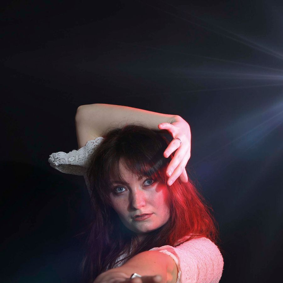 Foto van Suzanne Sanders met rood licht op haar gezicht en hand boven haar hoofd.