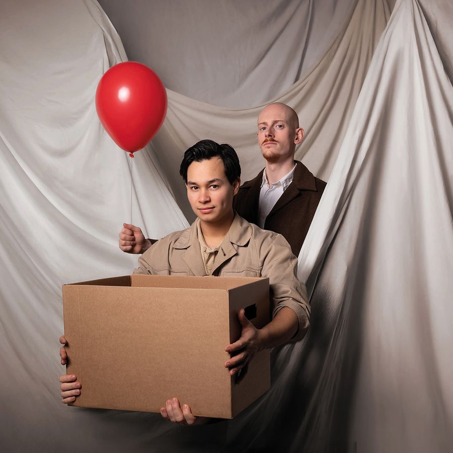 Foto van Niek en Guy. een houd een doos vast en de ander staat er achter met een rode ballon. 