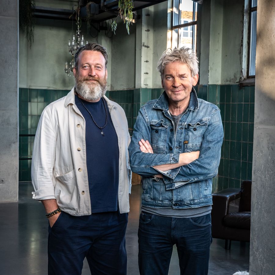 Twee mannen staan naast elkaar in een oud gebouw.