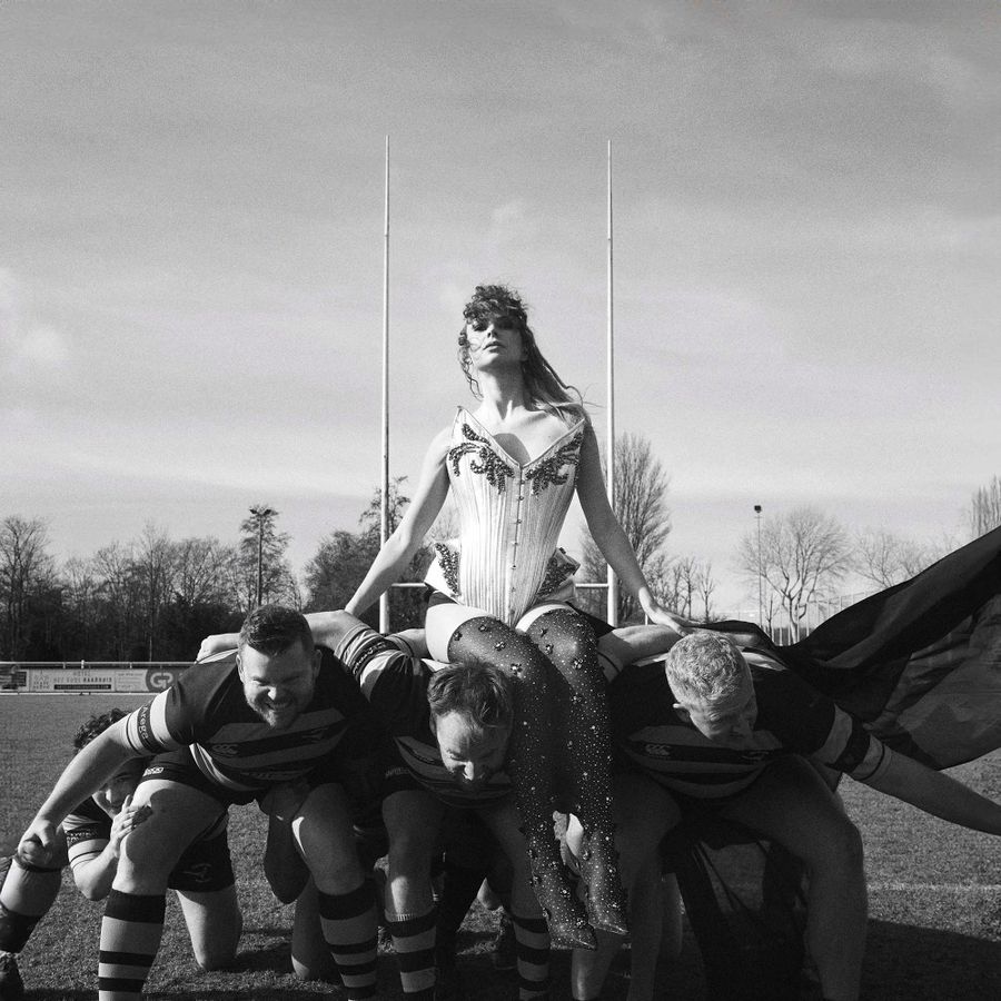 Zwart wit foto van een vrouw die op de schouders zit van drie mannen.