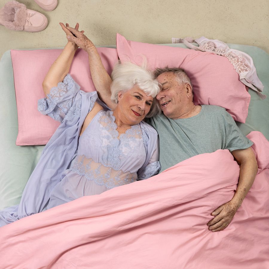 Een oudere man en vrouw liggen samen in bed.