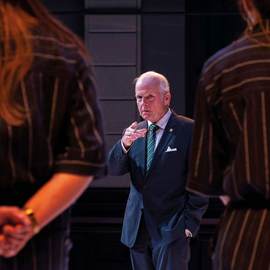 Een oude man wijst naar de camera.