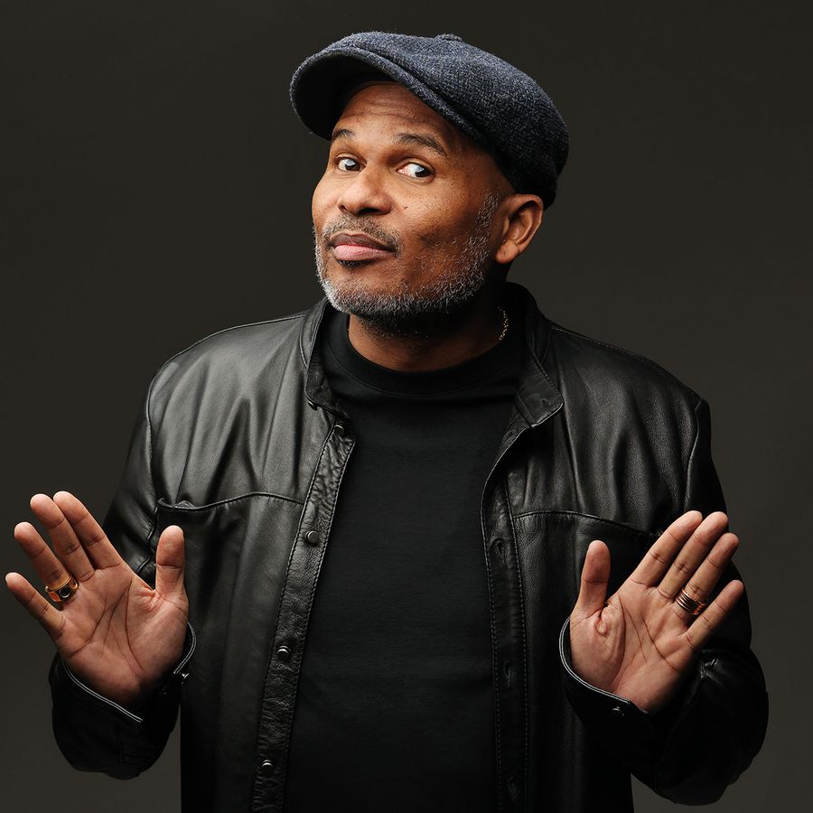 Roué kijkt geamuseerd naar de camera, met een donkere achtergrond.