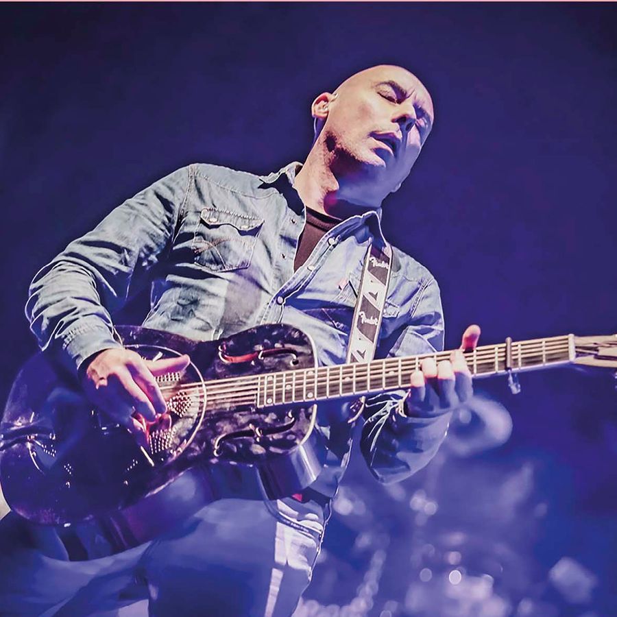 Een kale man aan het spelen op zijn gitaar.