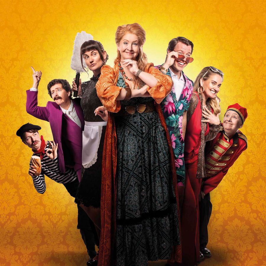 Vijf vrolijke mensen poseren samen voor een gele achtergrond.