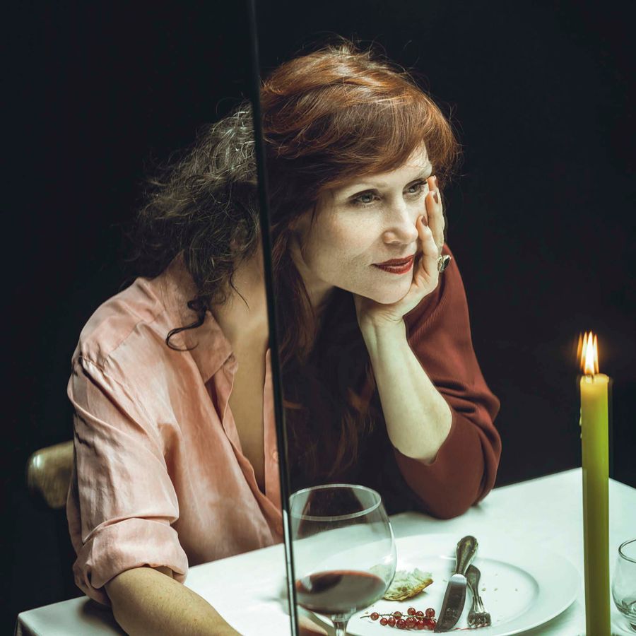 Een vrouw aan tafel met een glas wijn in haar hand.