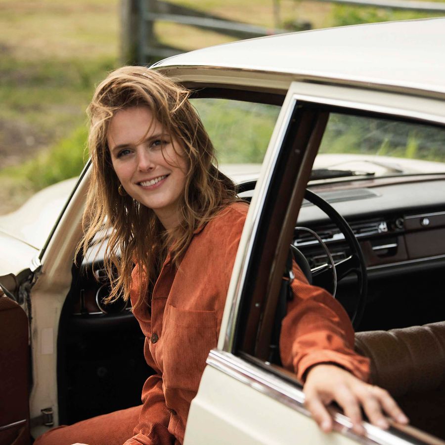 Maaike stapt lachend uit de auto.